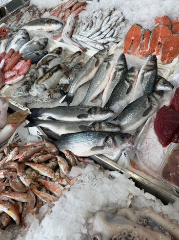 Interno di un ristorante con tavoli apparecchiati, decorazioni a forma di pesce sulle pareti e fiori.