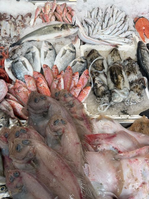 Piatto di frutti di mare: gamberi, carpaccio di pesce e tartare di tonno su un piatto blu.