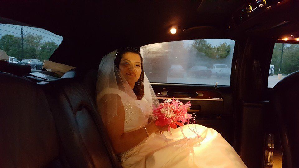 photo of a bride in the back of a limousine holding a pink boqouet