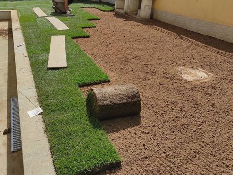 Una persona sta stendendo il manto erboso in un cortile vicino a una piscina.