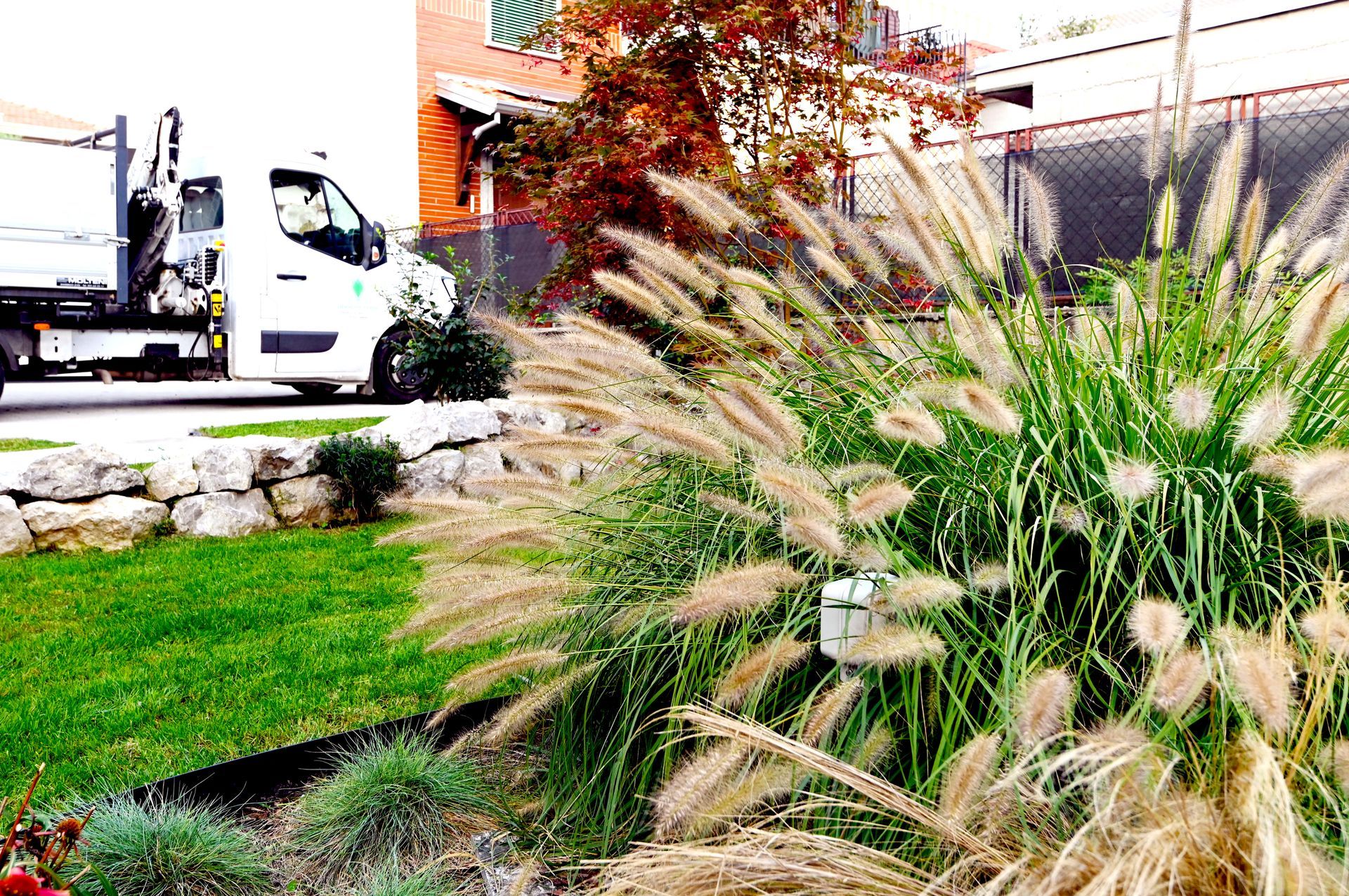 Un furgone bianco è parcheggiato in un vialetto d'accesso accanto a un cespuglio.