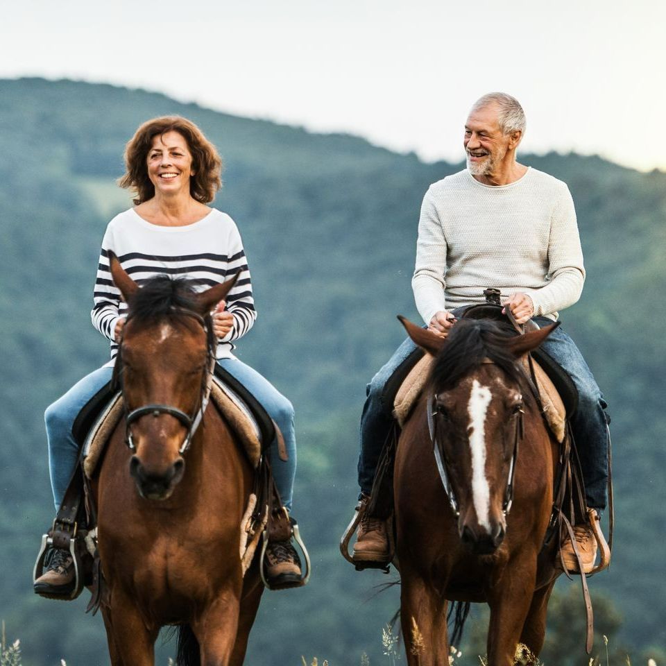 A man and a woman are riding horses in a field.