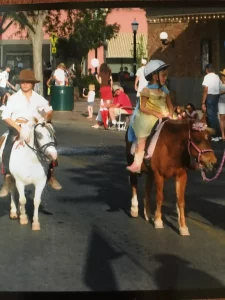 A group of people are riding ponies down a street