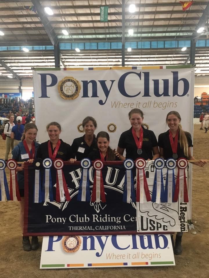 A group of young women holding a pony club banner