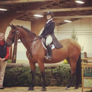 A woman riding a horse next to a sign that says tropical hots