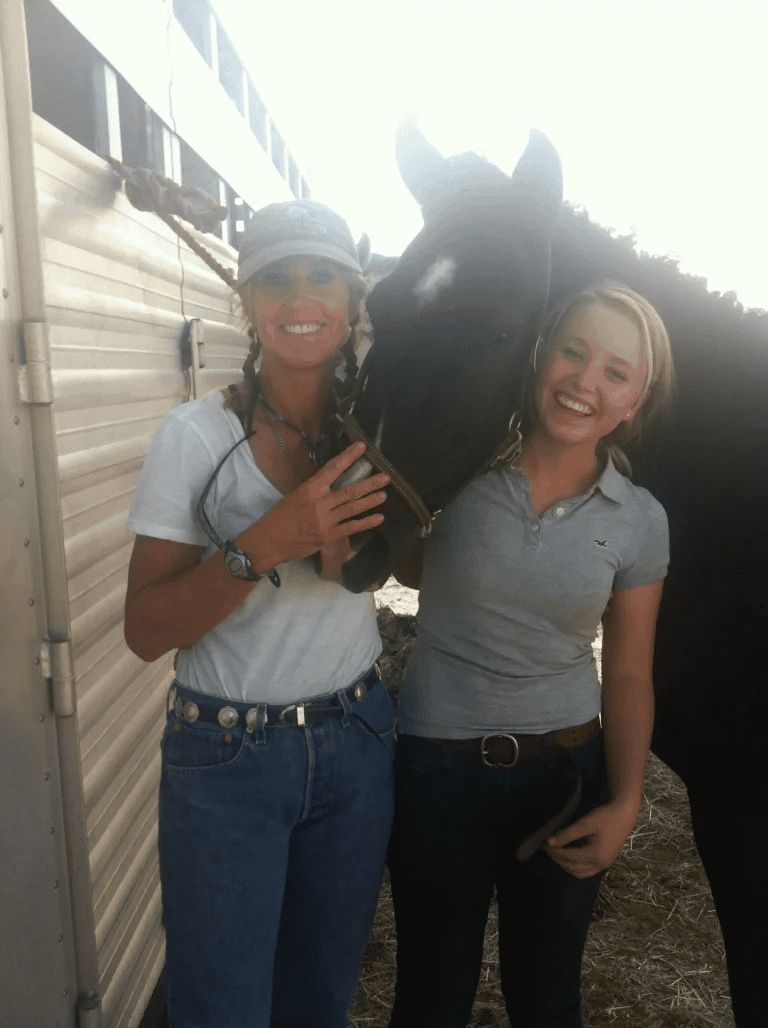 Two women are posing for a picture with a horse