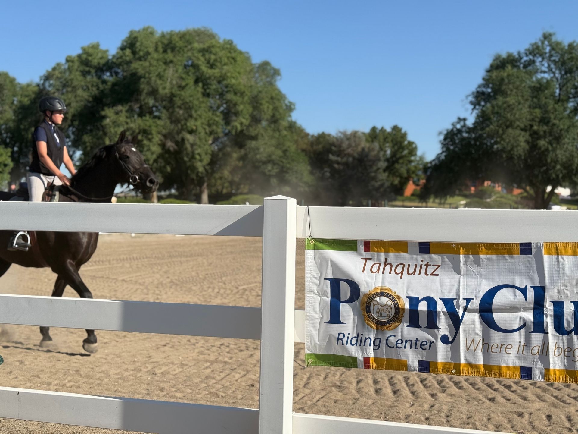 A man riding a horse behind a pony club sign