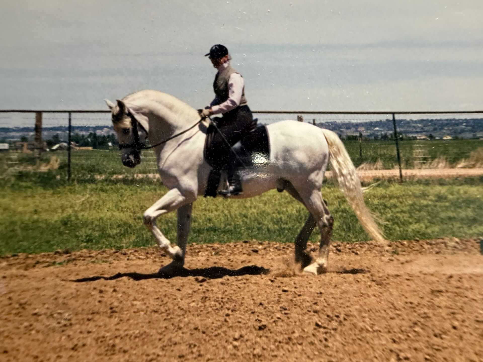 A woman is riding a brown horse in a dirt field.
