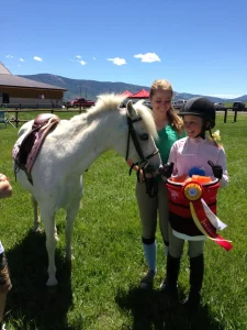 A little girl standing next to a white horse