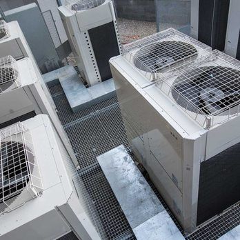 White air conditioning units on a metal grate roof.