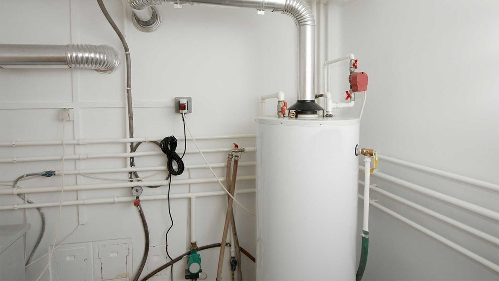 Water heater in white room with pipes and ventilation.