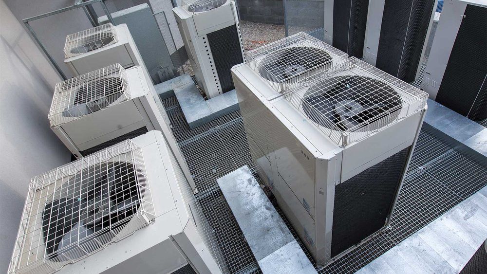 Air conditioning units, outdoors, on metal grates.