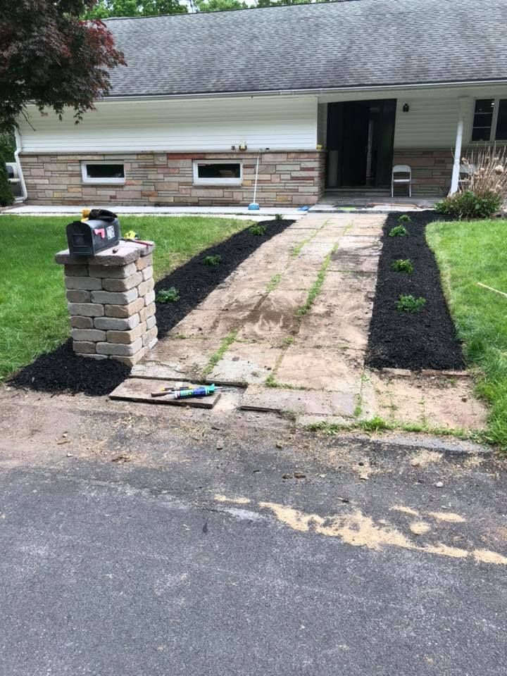 A house with a walkway and a brick pillar in front of it.