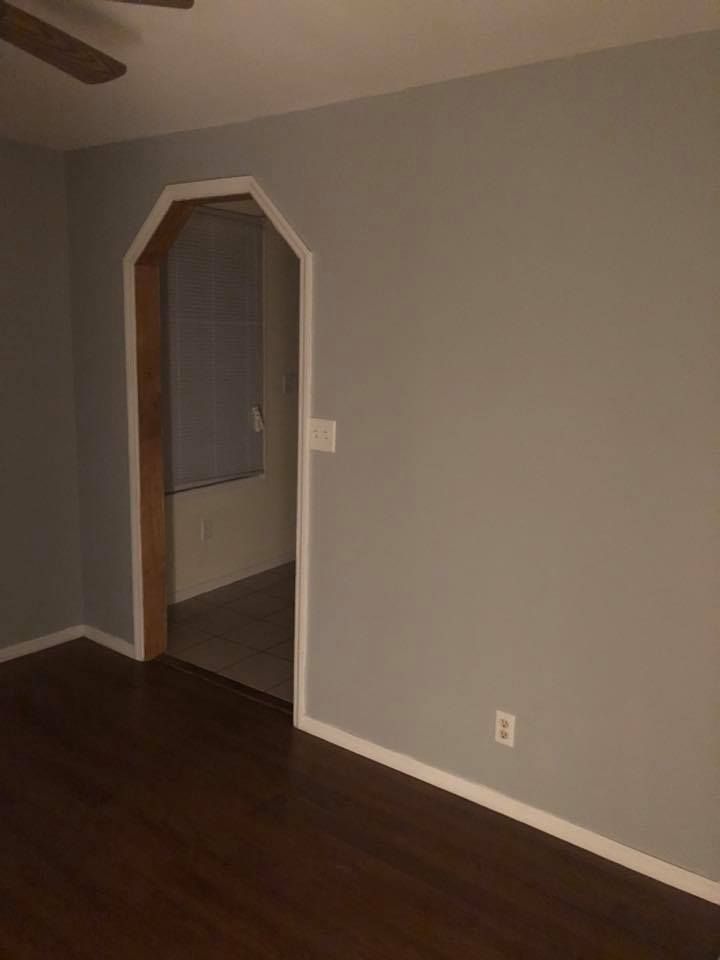 A living room with a ceiling fan and a doorway leading to a bathroom.
