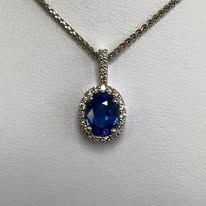 Sapphire pendant necklace with a blue gemstone surrounded by small diamonds on a silver chain.