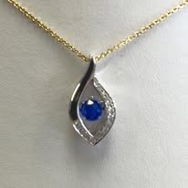 Gold necklace with a teardrop-shaped pendant featuring a blue gem surrounded by small clear stones.