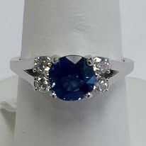Silver ring with a large blue sapphire center stone and two side diamonds.
