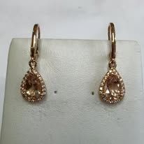 Gold teardrop earrings with peach-colored gemstones, displayed on a white surface.