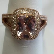 Rose gold ring with a square, blush-colored center stone and a halo of smaller stones.