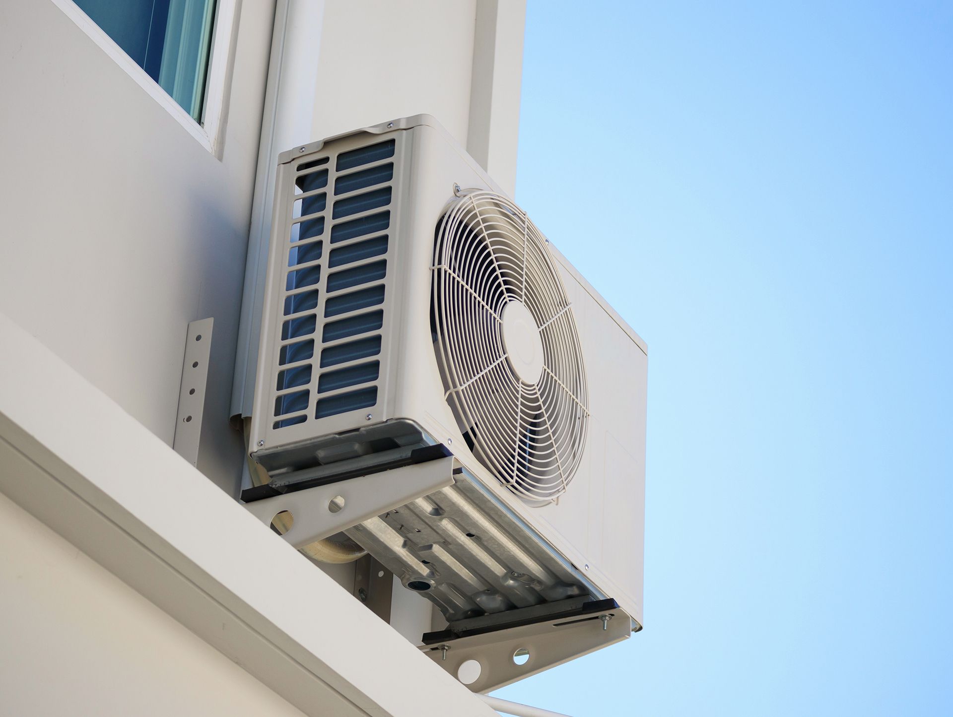 A white air conditioner is mounted on the side of a building.