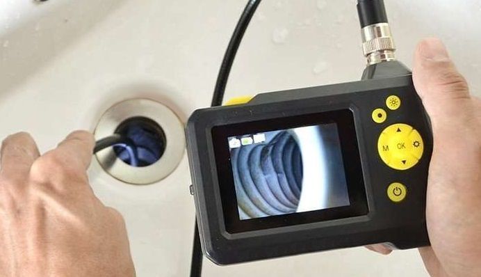 A person is using a camera to look into a sink drain.