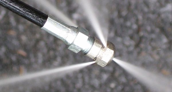 A close up of a high pressure hose spraying water.
