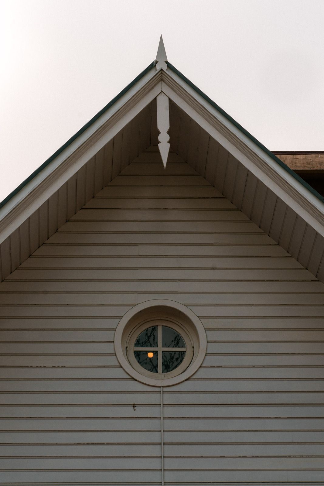 A white house with a round window and a pointed roof