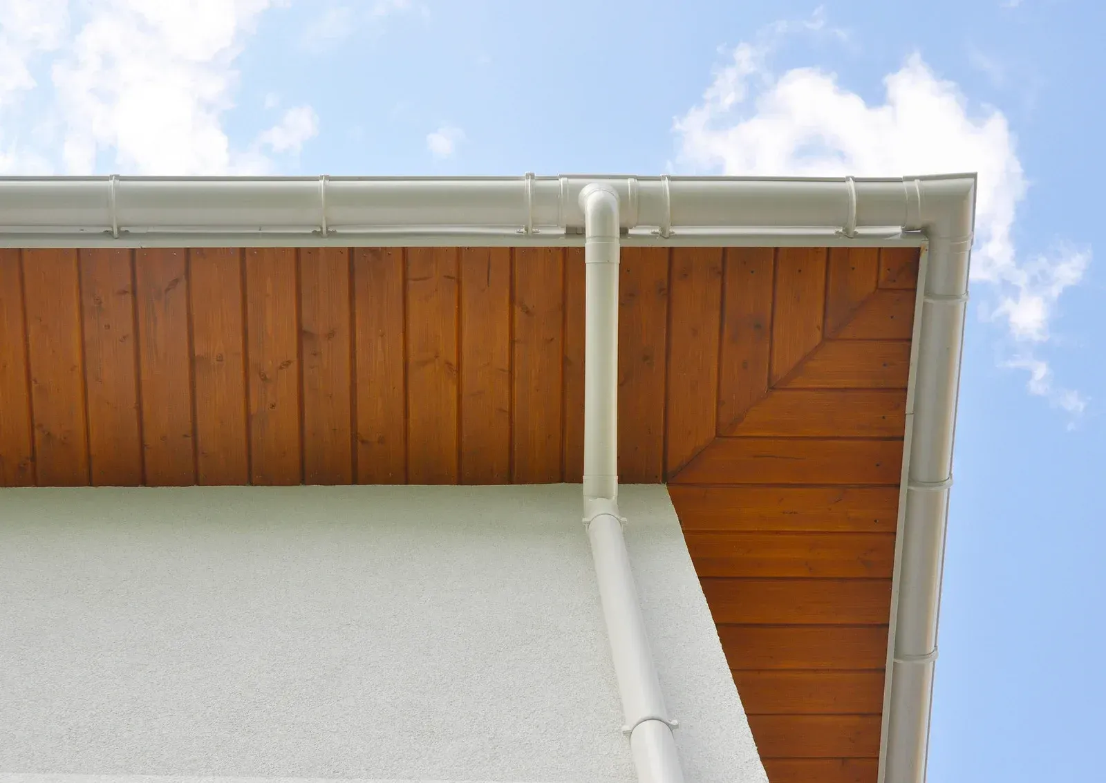 The roof of a house with a wooden ceiling and a white gutter.