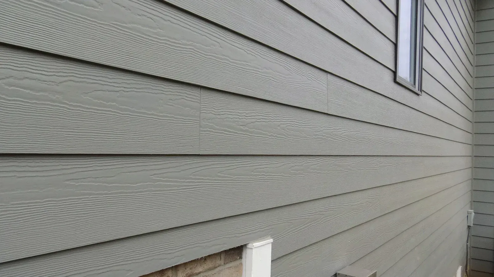 The side of a house with a gray siding and a window.