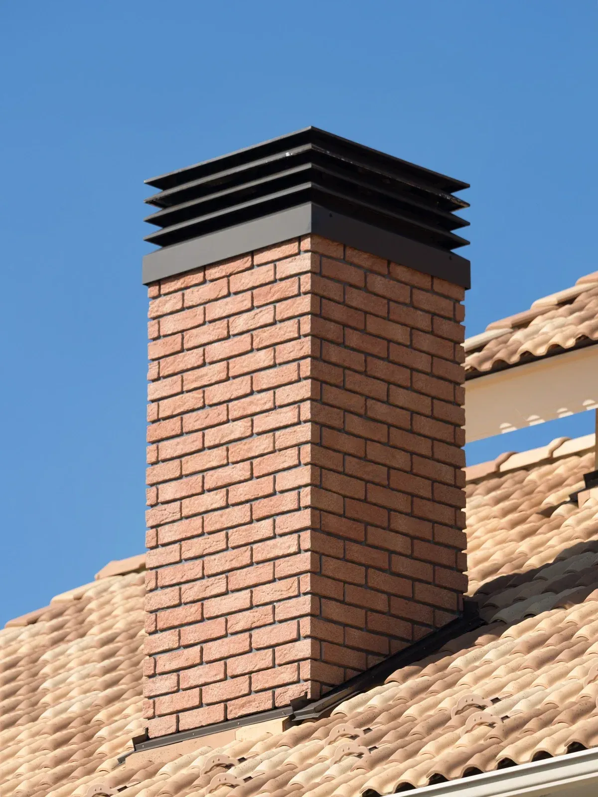 A brick chimney on top of a tiled roof