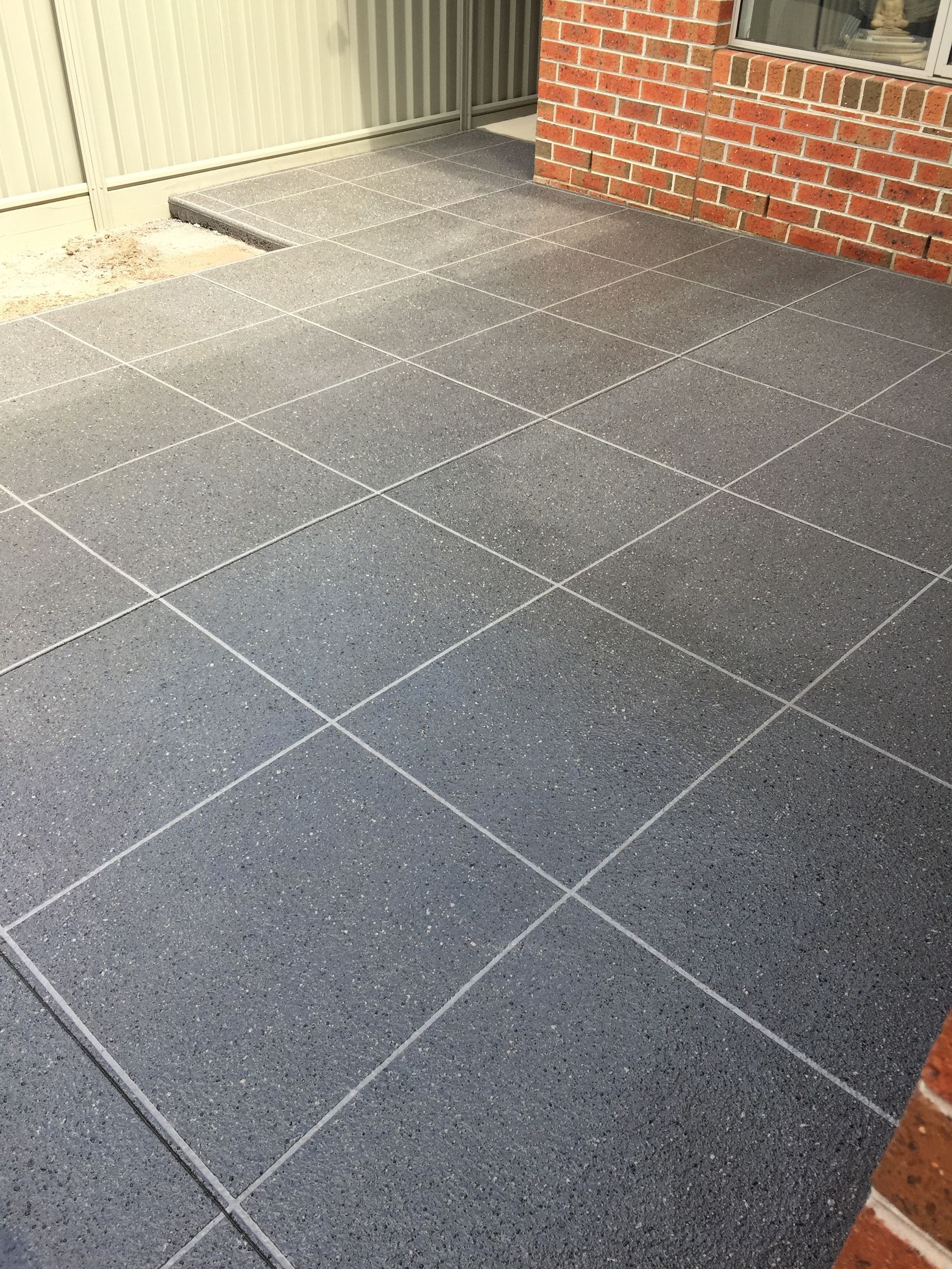 A close up of a gray brick floor with white spots.