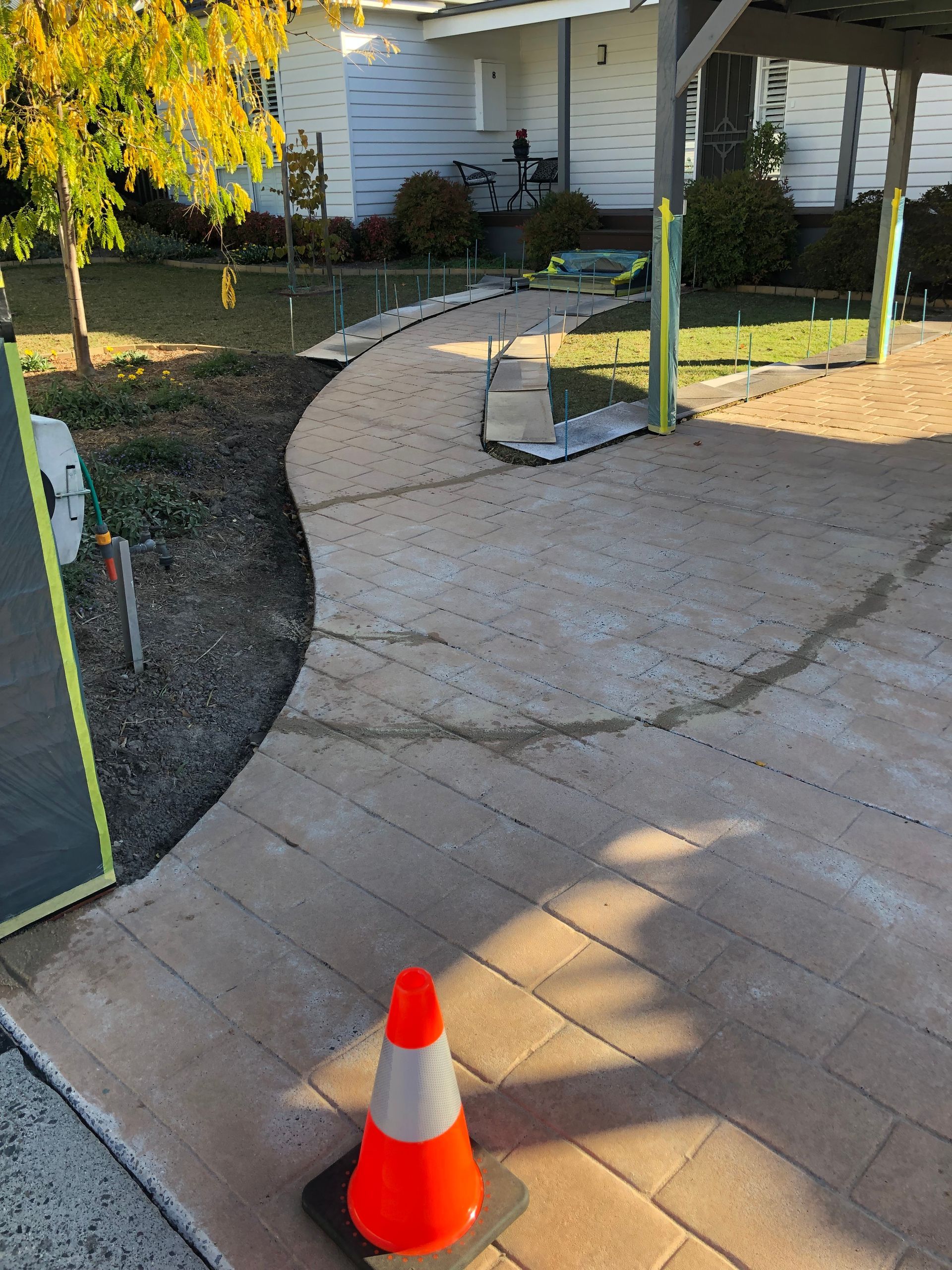 A brick house with a concrete walkway in front of it.
