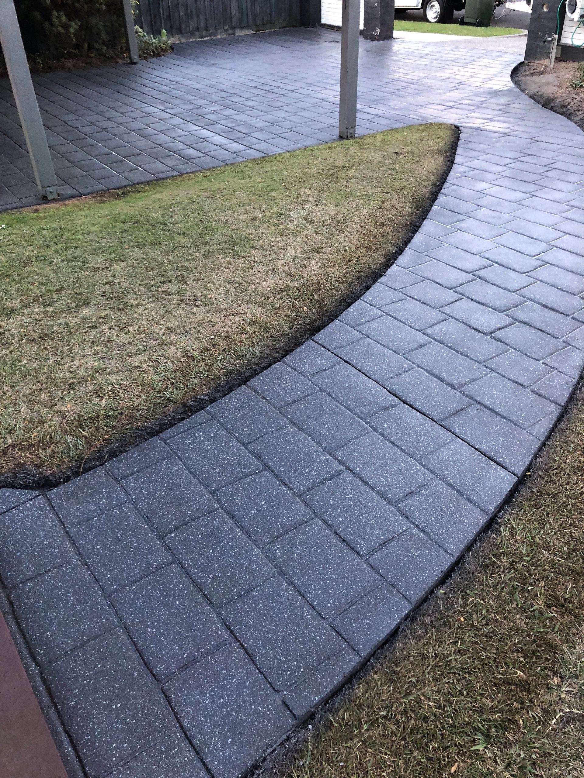 A driveway leading to a brick house with a garage.