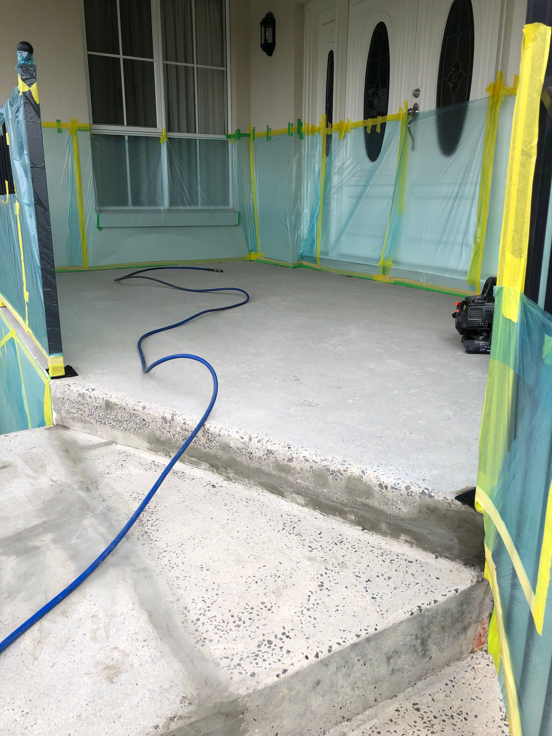 A concrete porch with a brick wall and a gate in front of a house.
