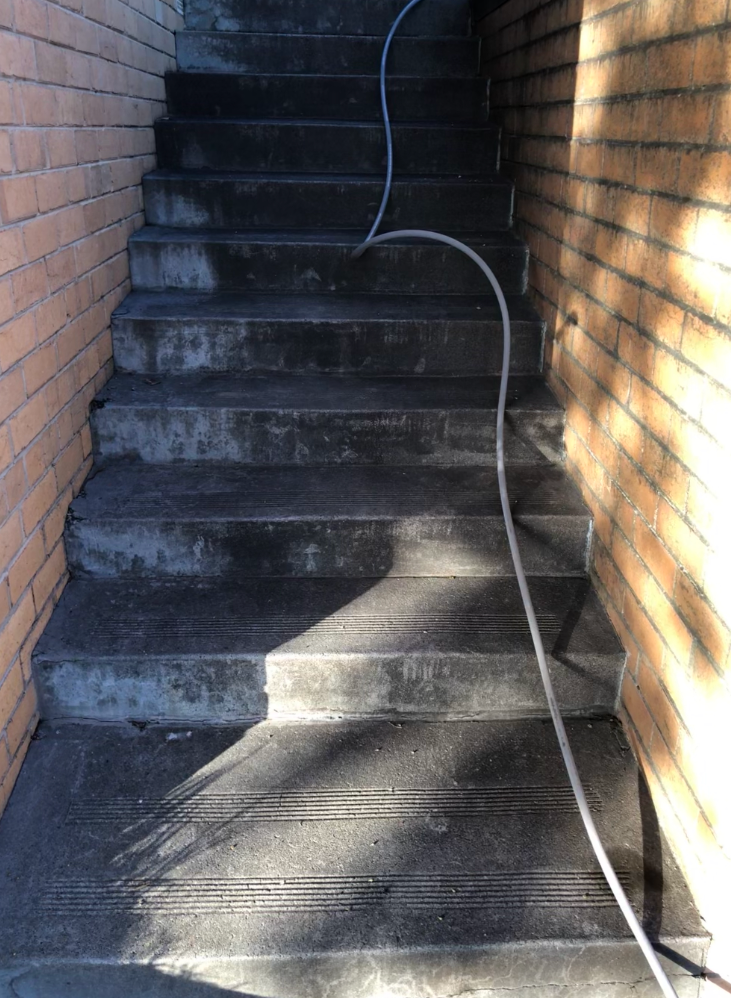A concrete walkway leading to a brick house.