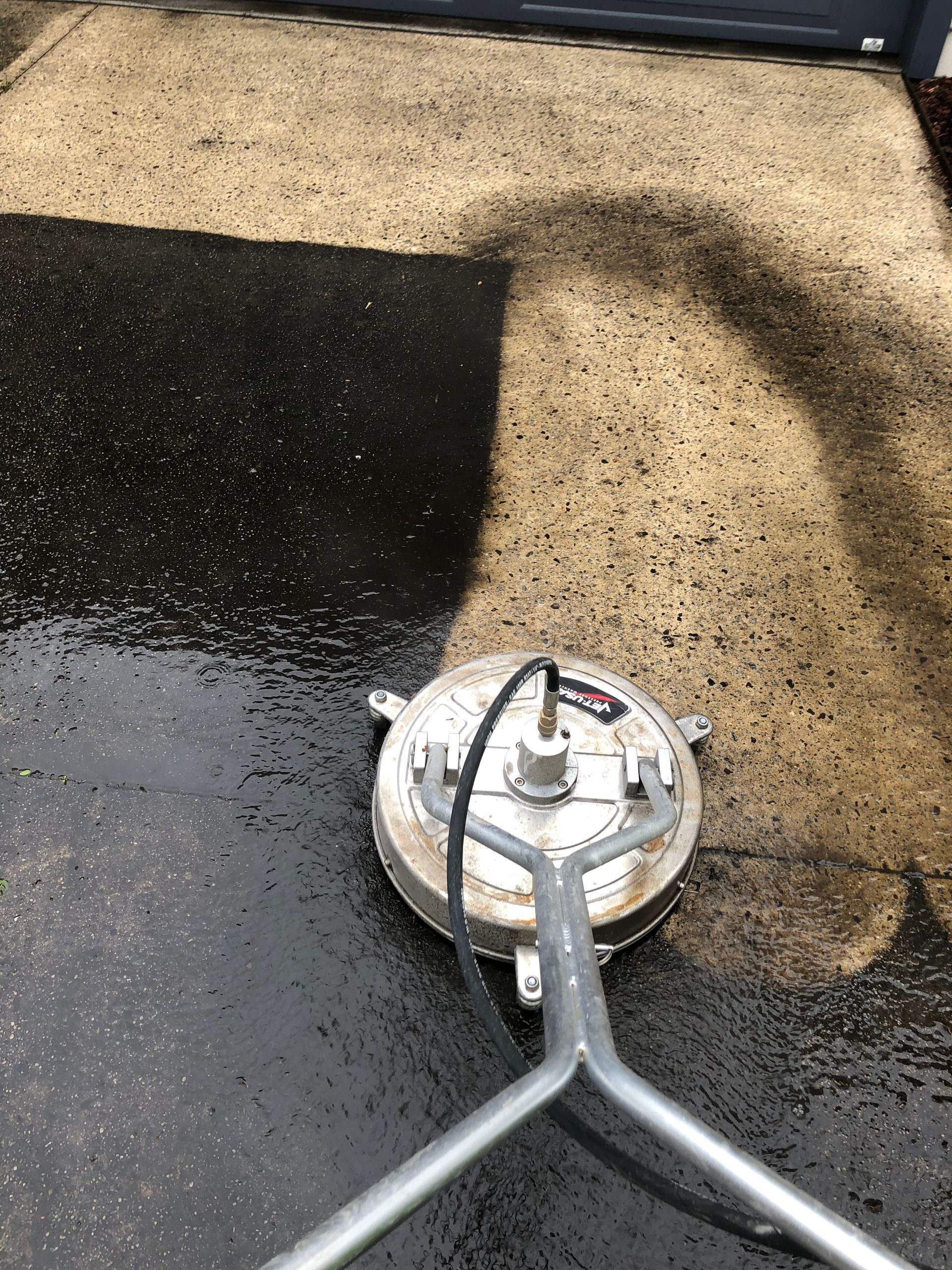 A man is cleaning a patio with a high pressure washer.