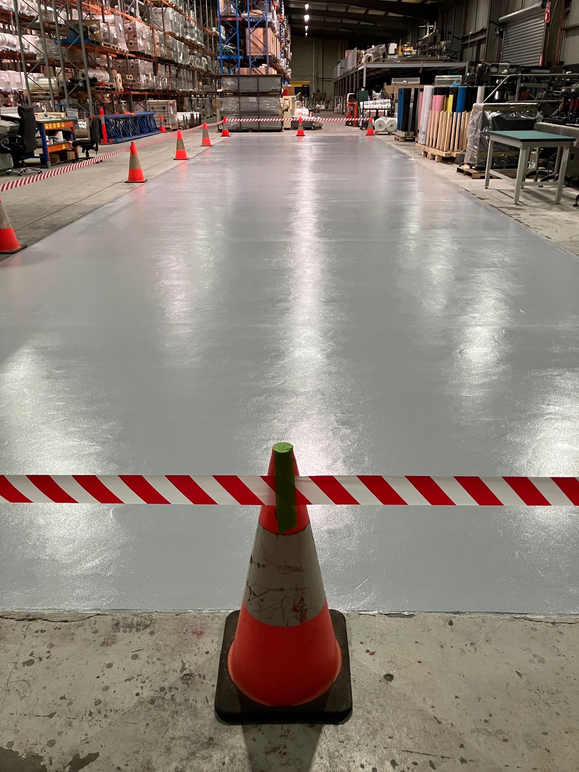 A person is painting a concrete floor with a roller.