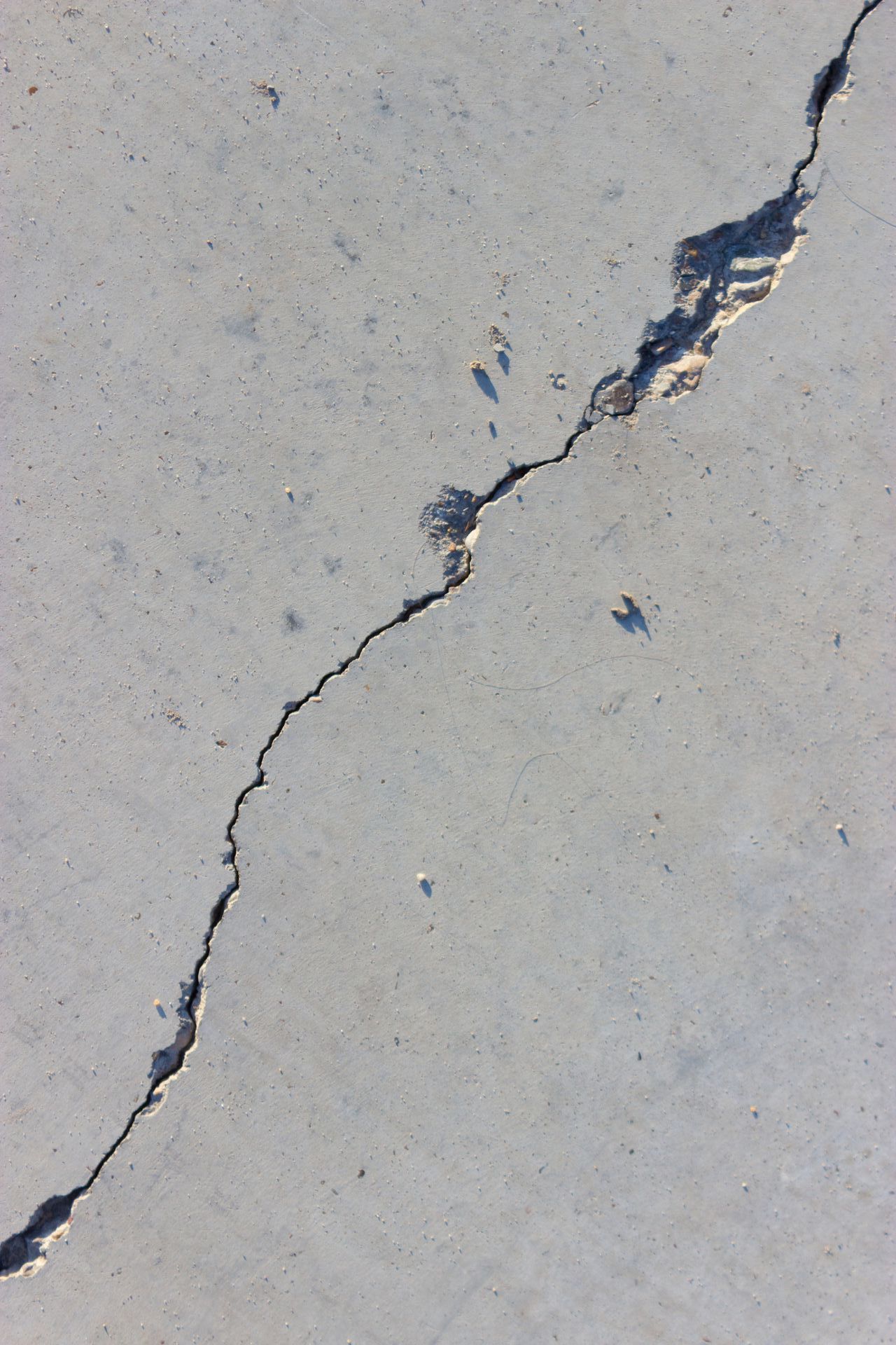 A person wearing orange gloves is using a trowel to spread concrete.