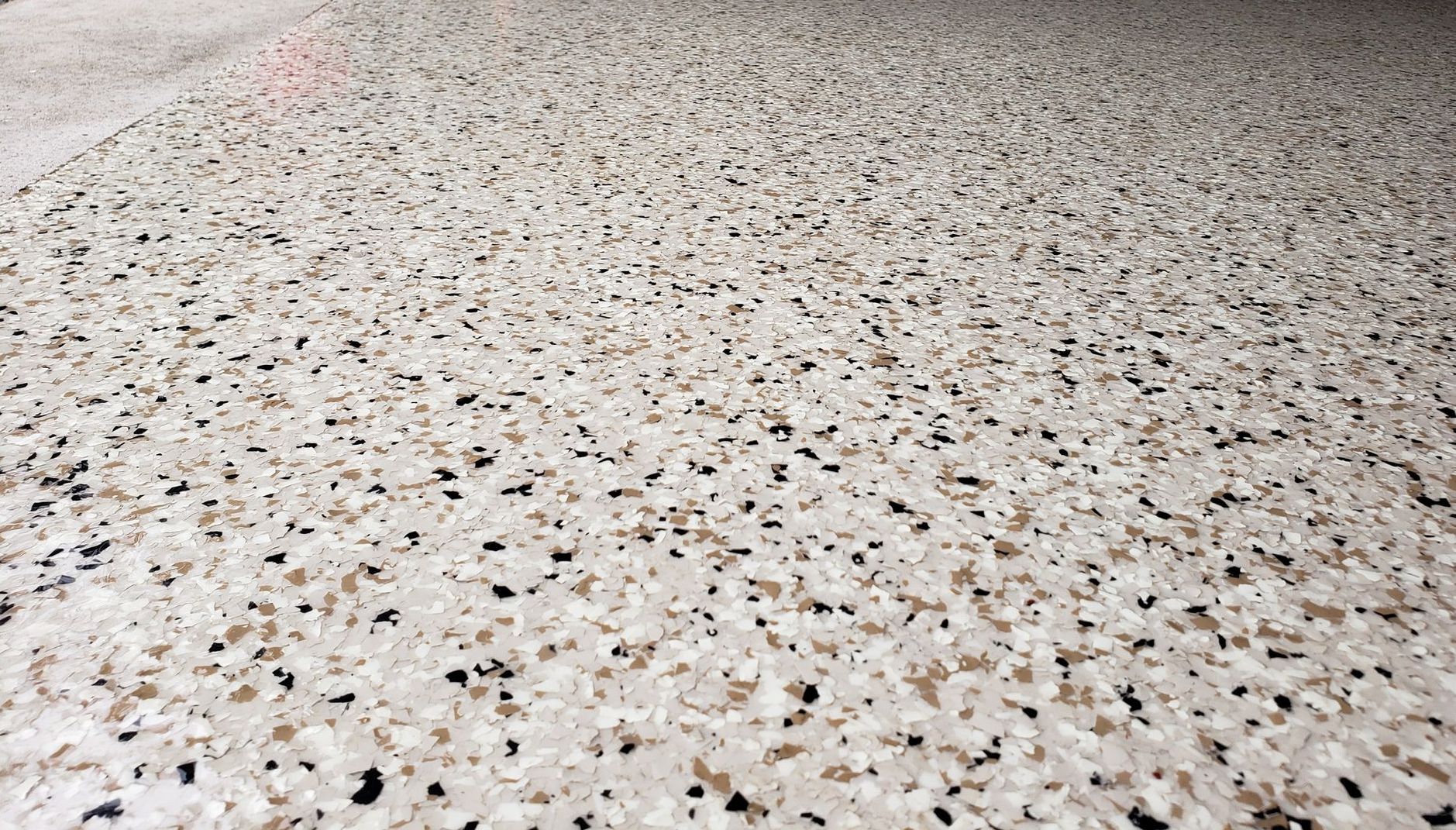 A red bucket is sitting on the side of a garage floor.