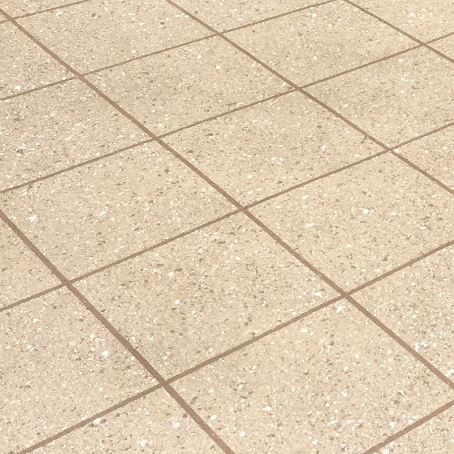 A white box is sitting on a tiled floor next to a brick wall.