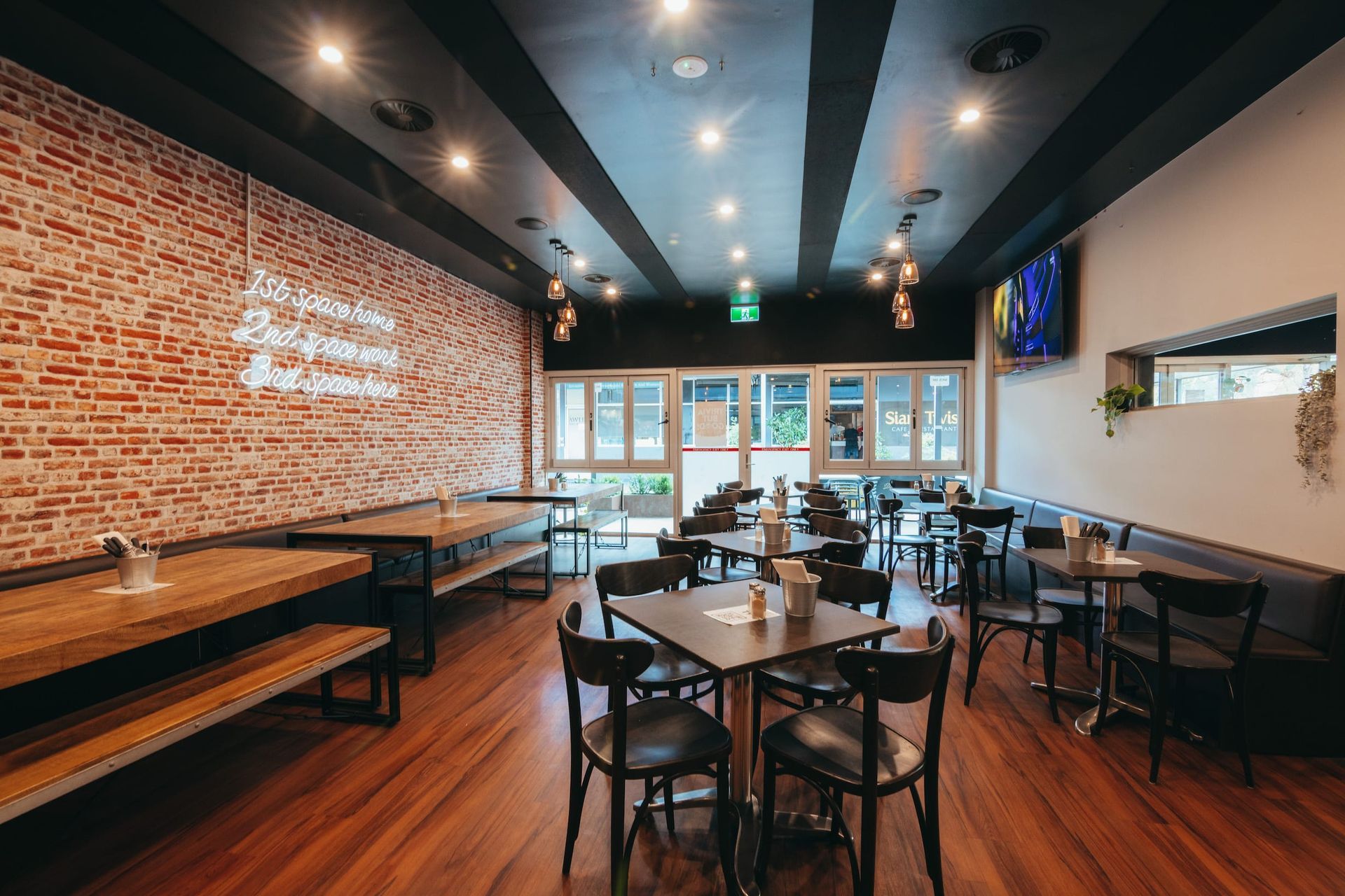 A restaurant with tables and chairs and a brick wall.