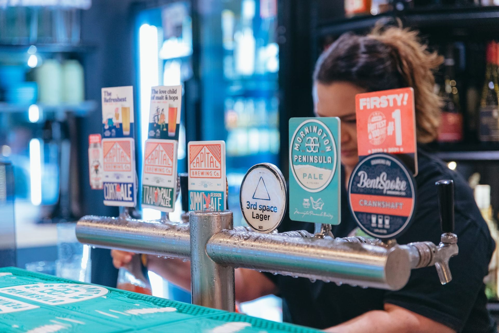 A woman is pouring beer from a tap in a bar.
