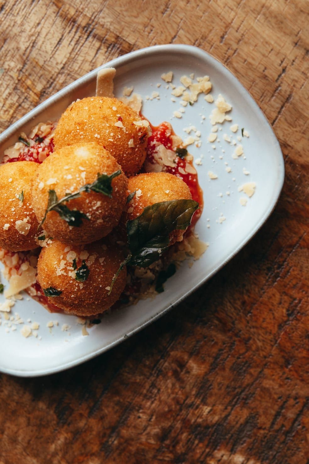 A white plate topped with fried food on a wooden table.