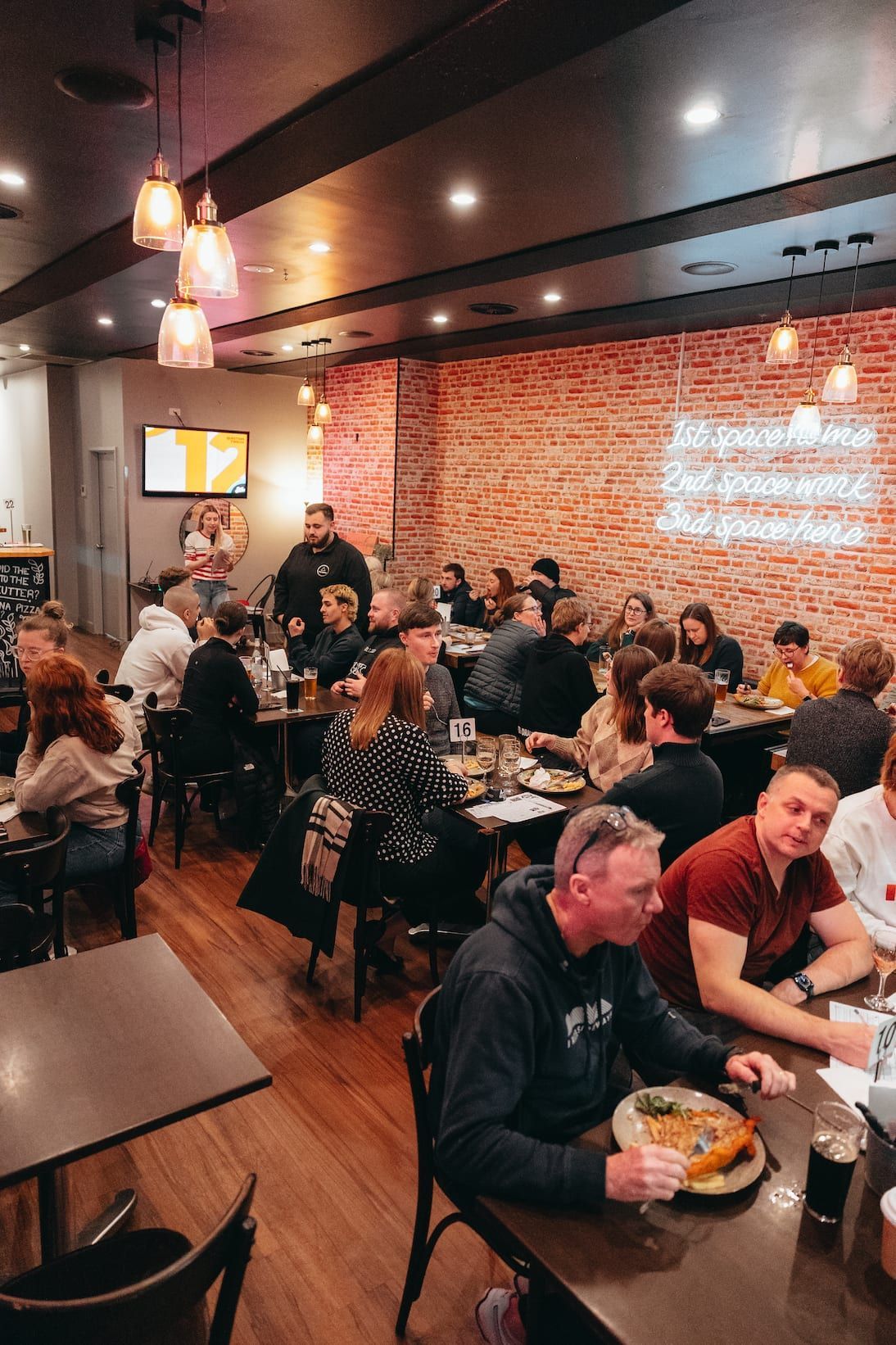 A group of people are sitting at tables in a restaurant eating pizza.
