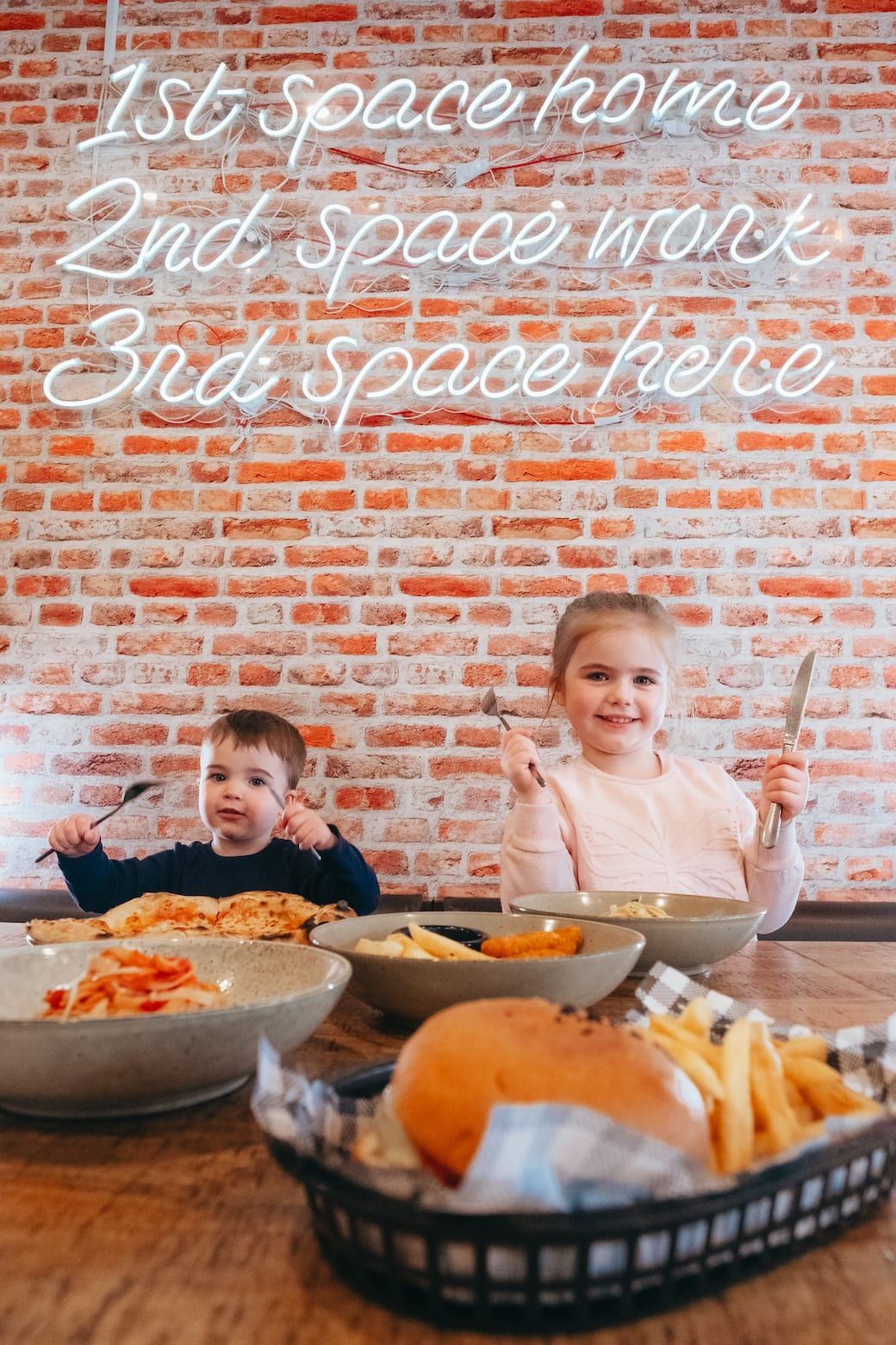 A boy and a girl are sitting at a table eating food.