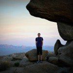 A man is standing on top of a rocky hill.
