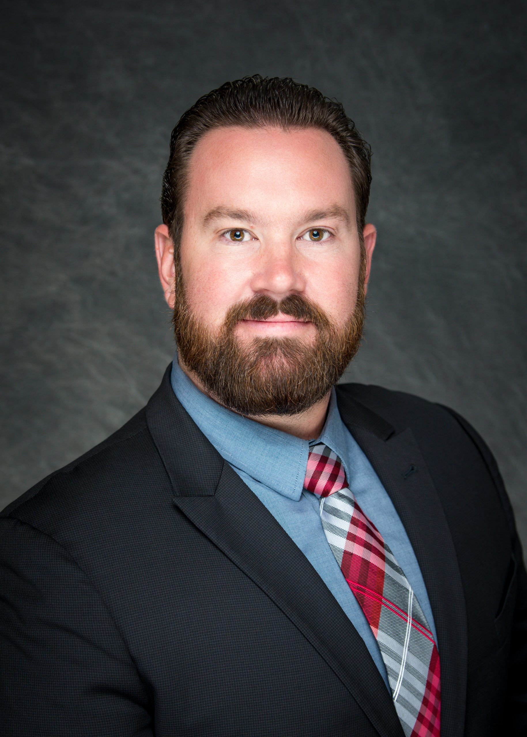 A man with a beard is wearing a suit and tie.