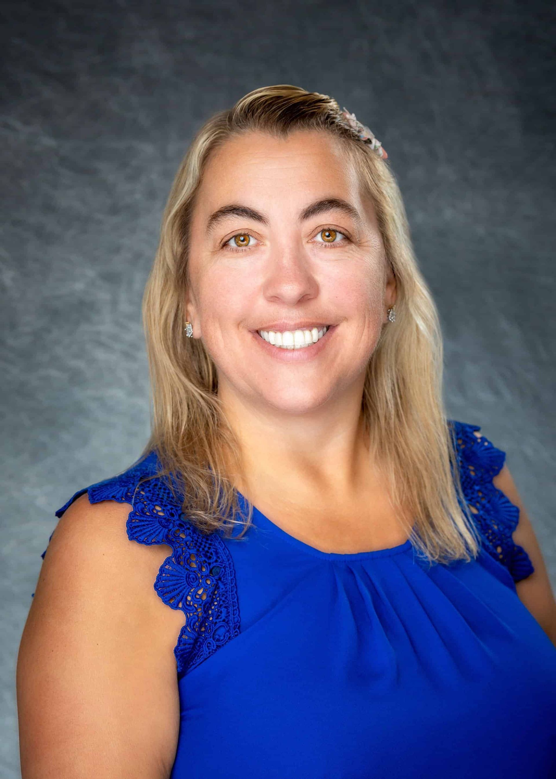A woman in a blue shirt is smiling for the camera.