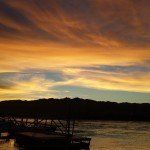 A sunset over a body of water with a dock in the foreground.