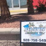 A sign for baron landscaping is sitting on the side of the road.